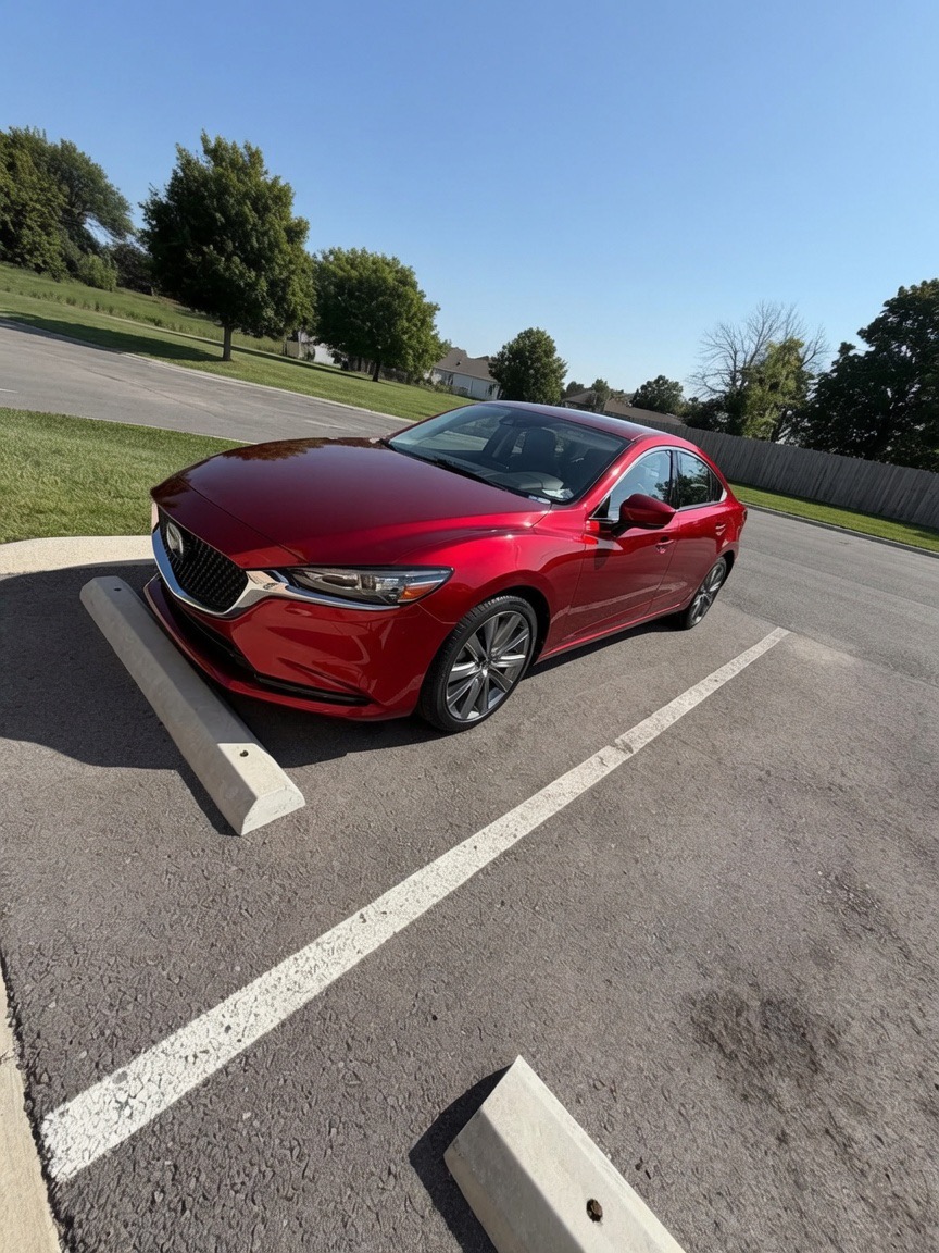 Red Mazda sedan after exterior detail with deep gloss.