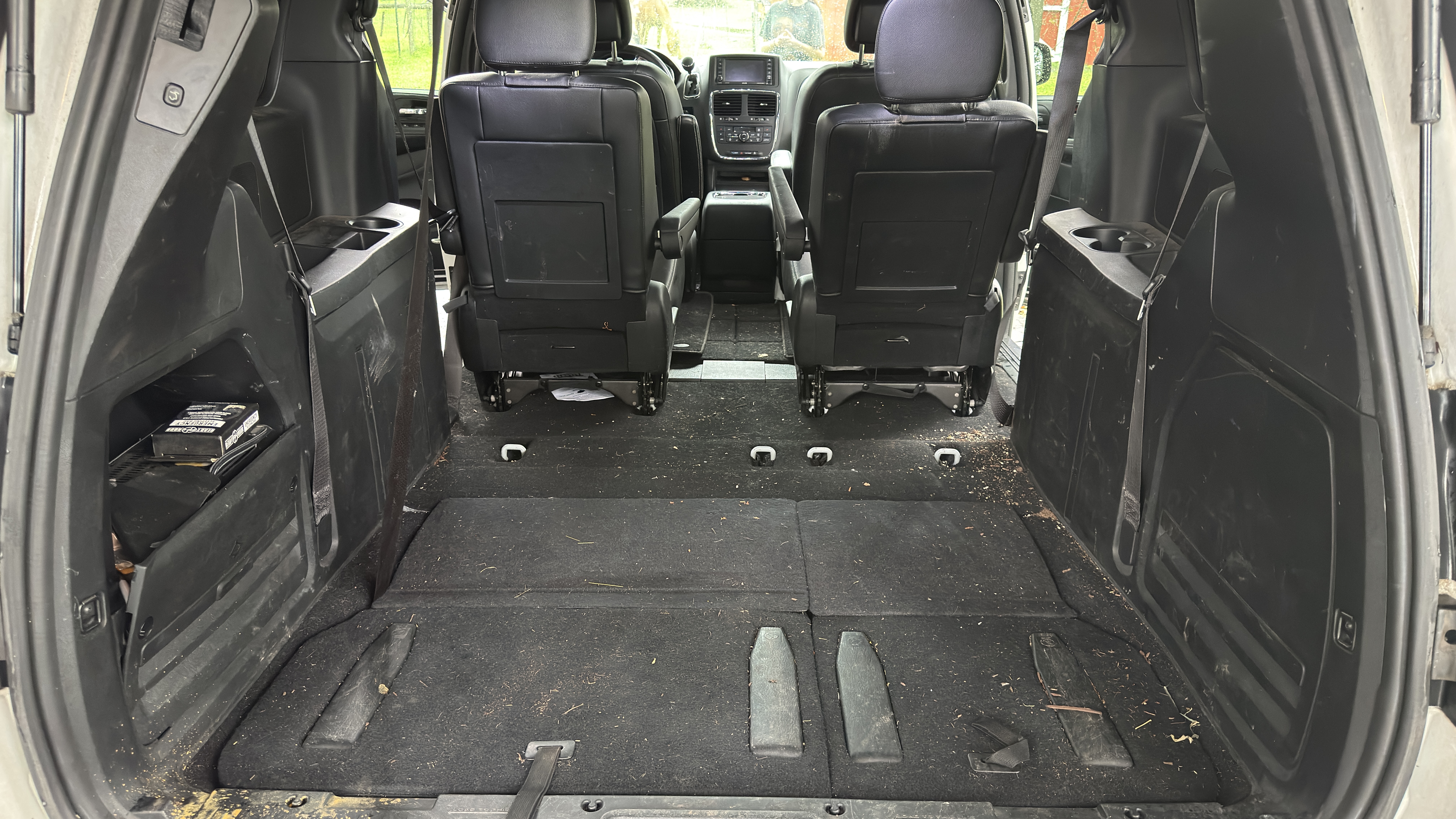 Before: dirty minivan cargo area with debris.