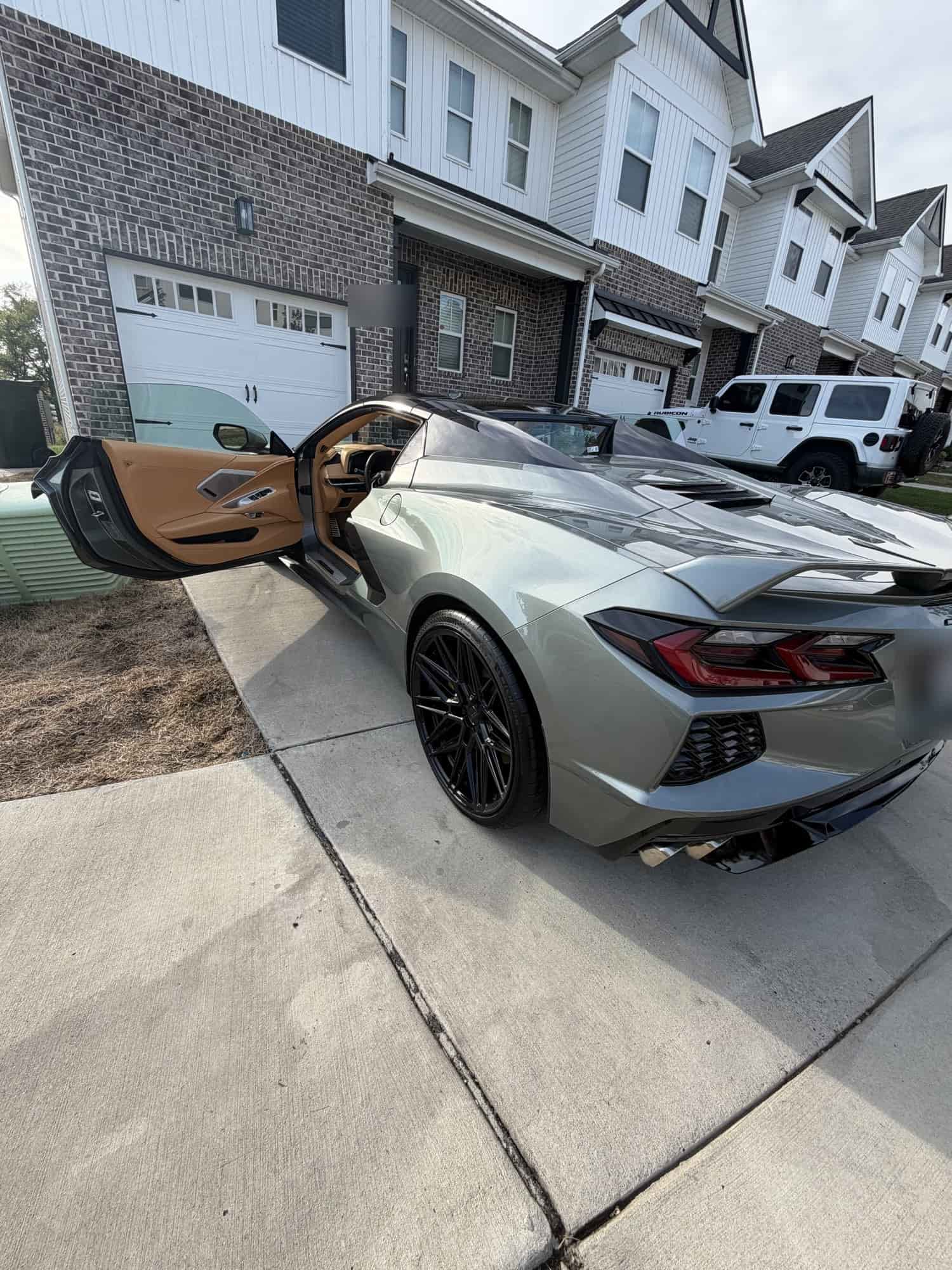 Rear of a gray Corvette C8 with the door open