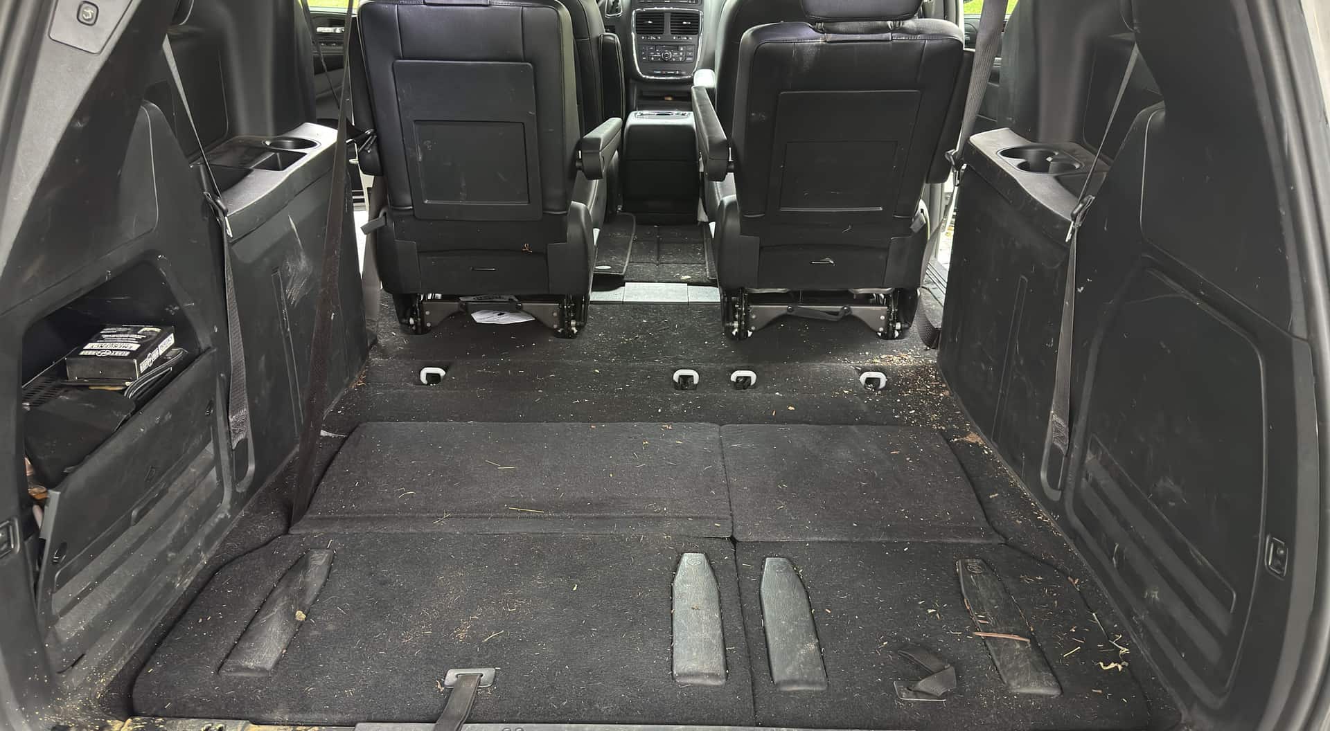 Minivan cargo floor covered in debris before vacuuming