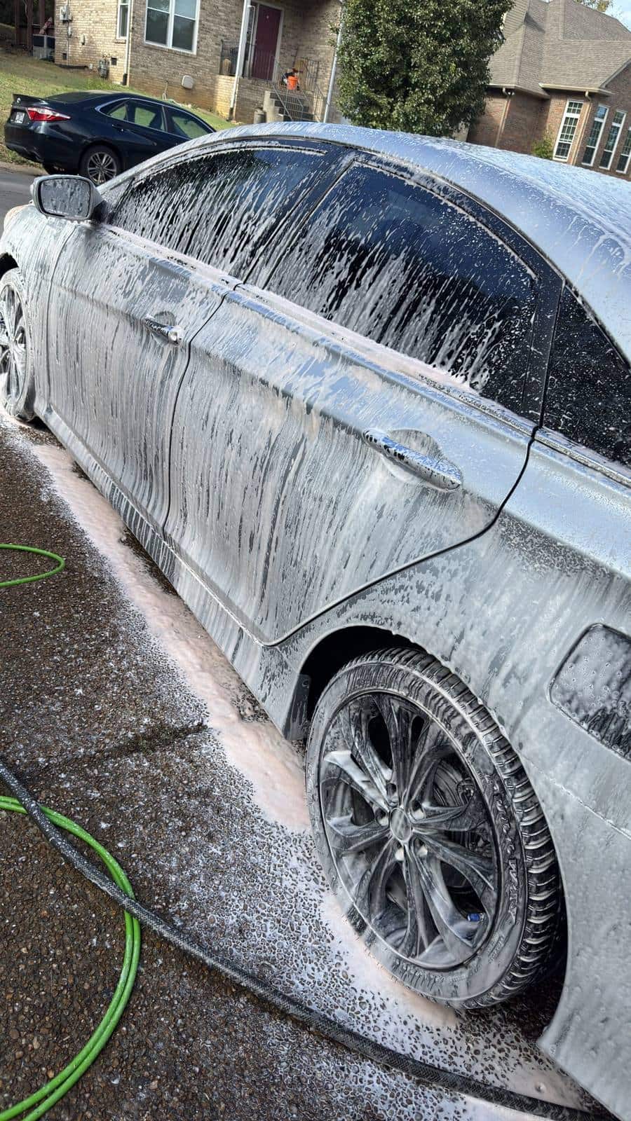Silver sedan covered in pink foam, seen from the side