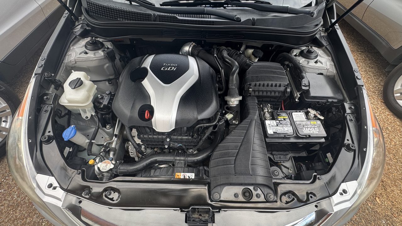 Clean engine bay of a 2014 Hyundai Sonata 2.0T in daylight, plastics and hoses dressed, engine cover on.