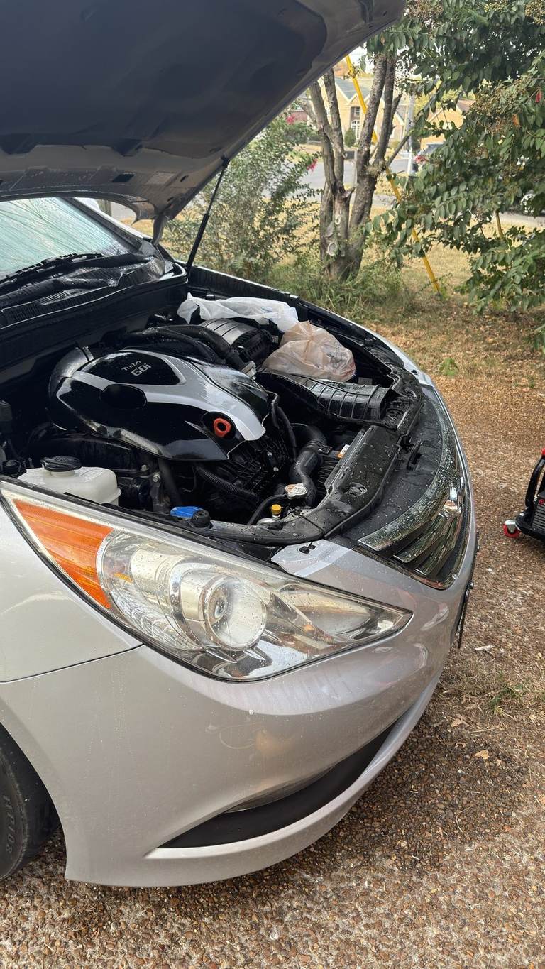 Plastic bags covering the battery and connectors in a 2014 Hyundai Sonata 2.0T engine bay before degreaser.