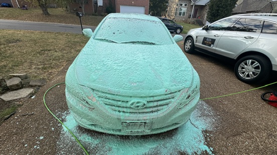 Hyundai Sonata covered in teal foam, seen from the front